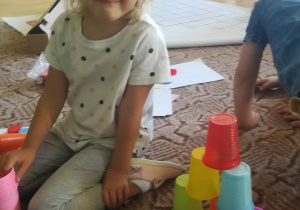 Dziewczynka zbudowała wieżę z kolorowych kubków